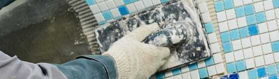 Pool Tile Repair This image shows a man installing new pool tiles.