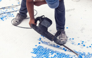 This image shows a man removing the old pool tiles.