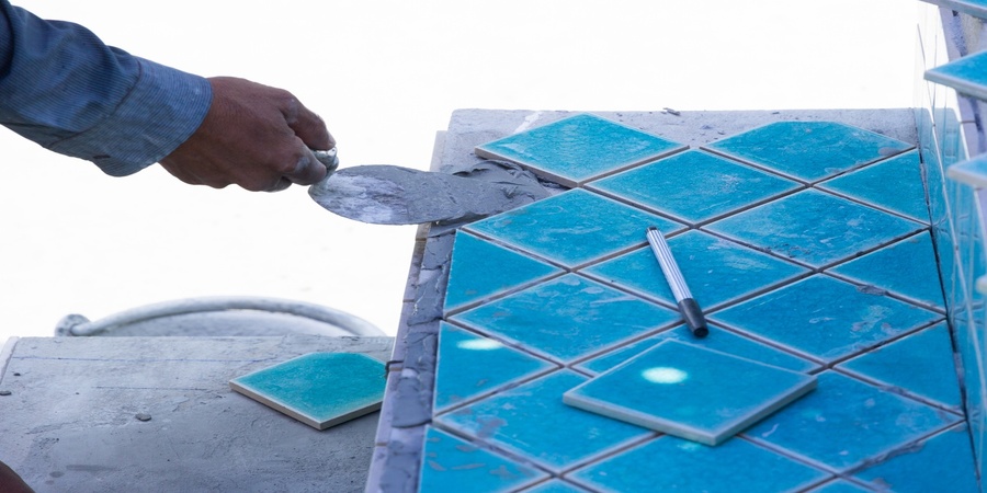 This image shows a man installing pool tile.